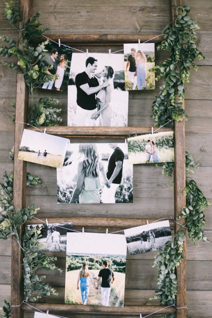 an old ladder is decorated with photos and greenery to hang on it's sides