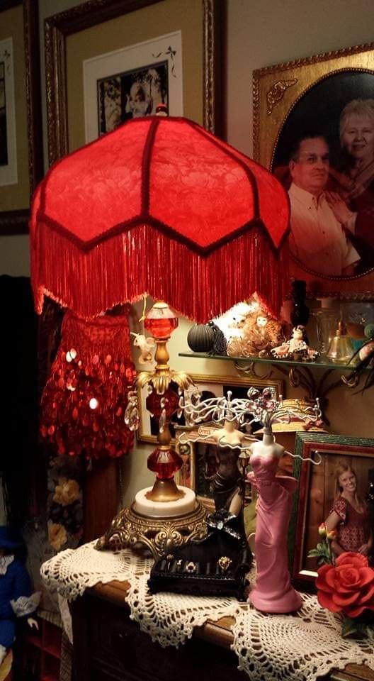 a red lamp sitting on top of a table next to pictures and other items in a room