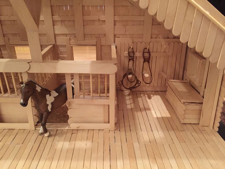 a toy horse is standing in the middle of a wooden room with stairs and railings