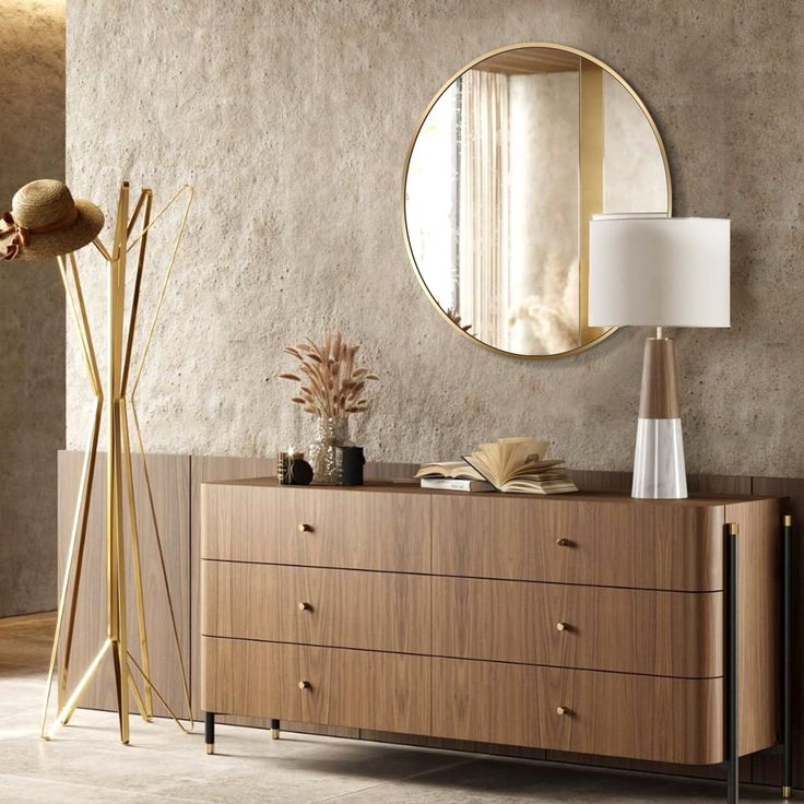 a living room with a large mirror on the wall next to a dresser and lamp