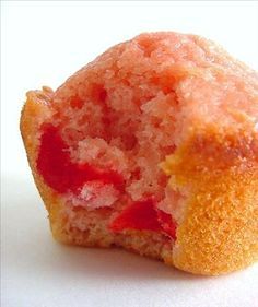 a half eaten strawberry muffin sitting on top of a white table