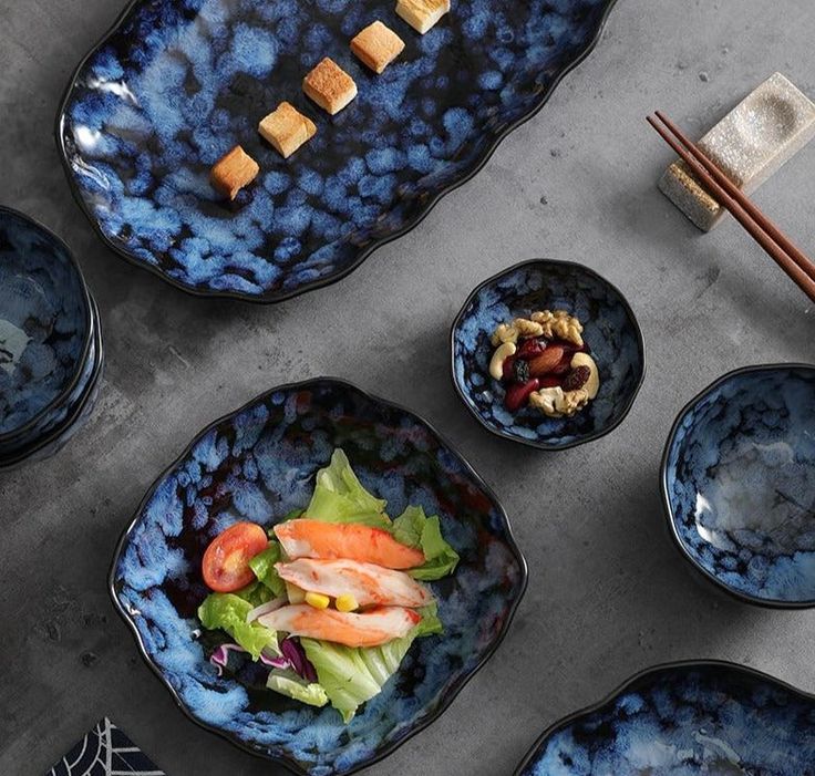 several blue bowls filled with food and chopsticks