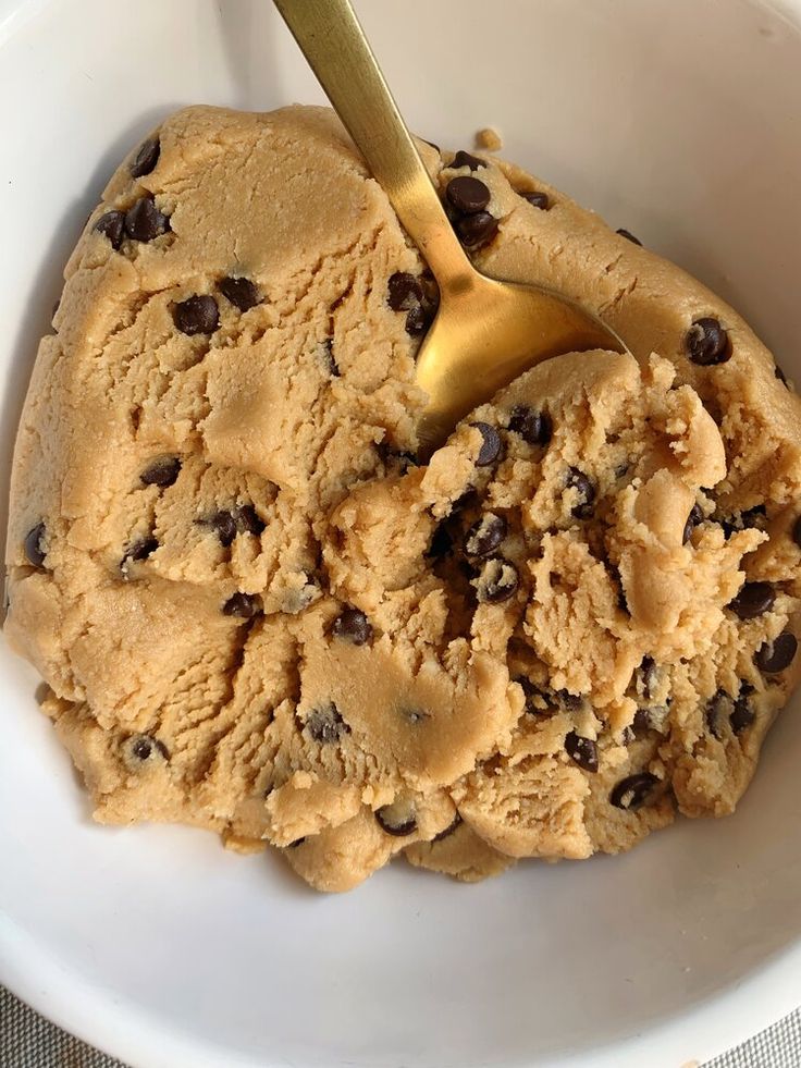 a scoop of ice cream in a bowl with chocolate chips and a gold spoon on top