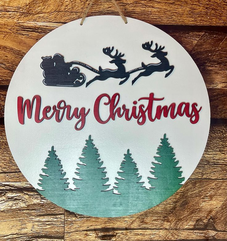 a merry christmas sign hanging from the side of a wooden wall with trees and sleigh