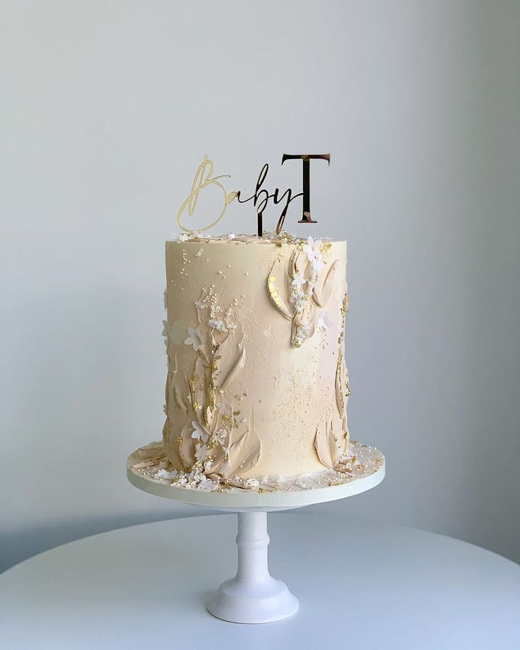 a wedding cake with white frosting and gold leaves on top is decorated with the initials t and b