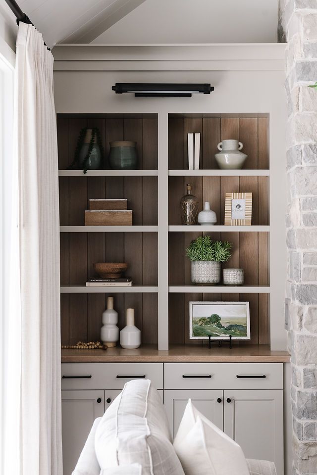 a living room filled with lots of furniture and bookshelves next to a brick wall