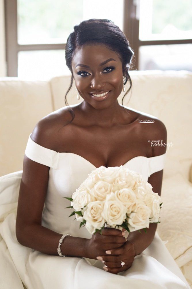 a woman sitting on a couch holding a bouquet of white roses in her right hand