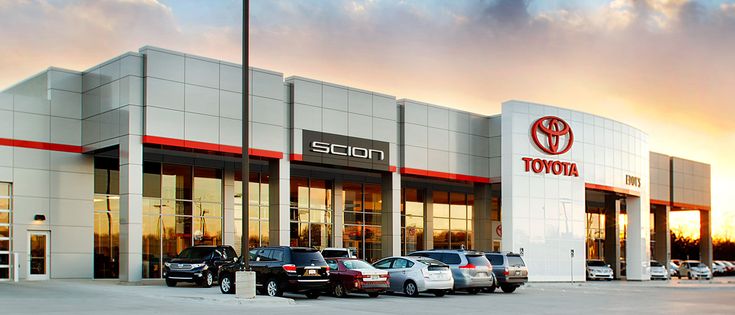 several cars parked in front of a toyota dealership with the sun setting behind them