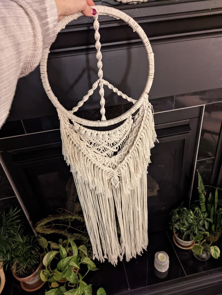 a person is holding a white macrame dream catcher