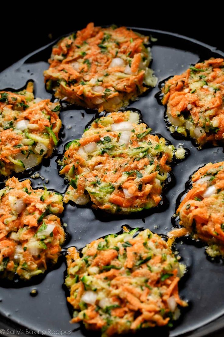 carrot and broccoli fritters on a black plate with some seasoning