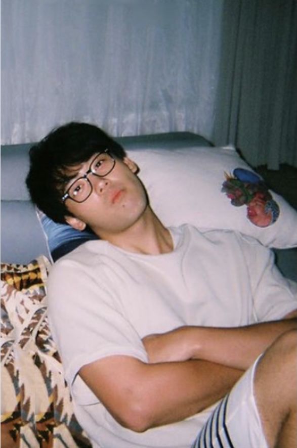 a man laying on top of a bed wearing glasses