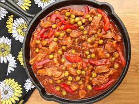 a pan filled with meat and vegetables on top of a wooden table