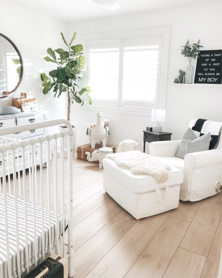 a baby's room with white furniture and decor on the walls, including a crib