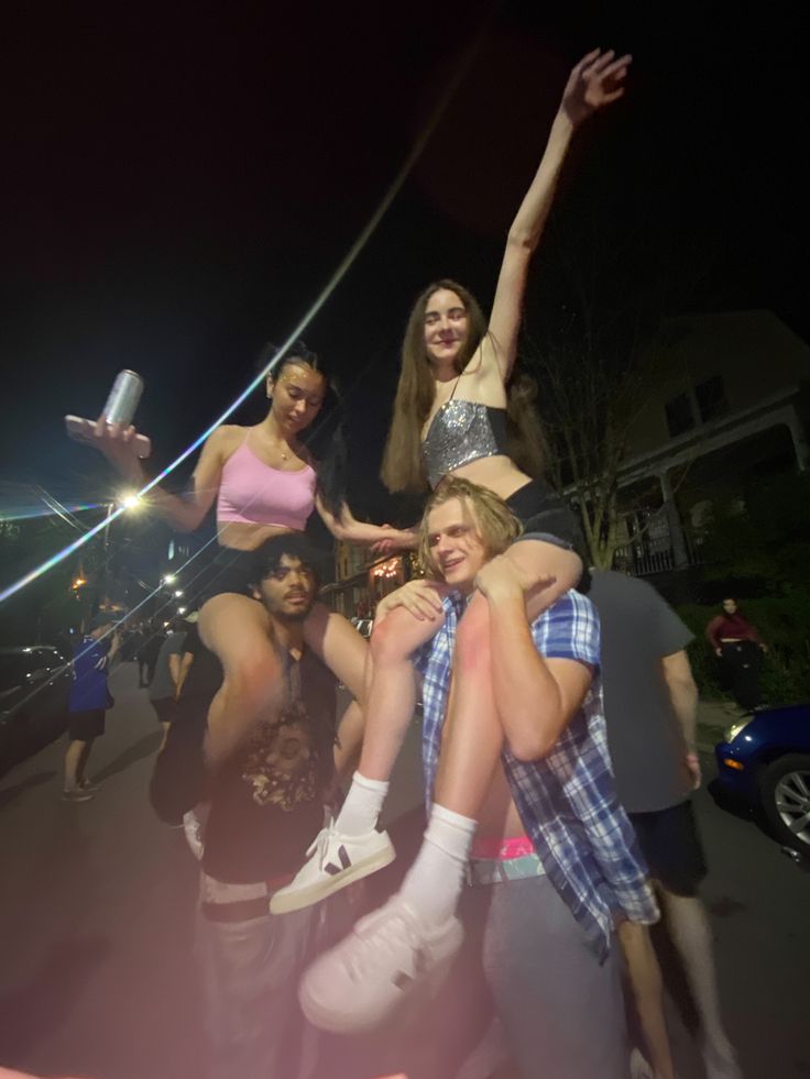 a group of people standing around each other in front of a car at night time