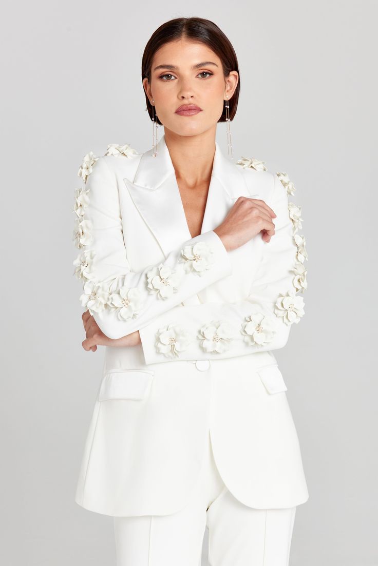 Leonie White Blazer Women's Clothing > Blazer. DESCRIPTION &  FEATURES    LEONIE   is a structured, sculpting single-breasted tailored suit jacket crafted from exclusively designed crepe with a contrast satin collar and pockets. It is cut to a structured fit with shoulder pads, large floral appliqués down both sleeves with faux pearl detailing at the centre of each flower, functional flap satin detailed pockets, silhouette-enhancing seam detailing, and finished with a satin button closure. White Blazer Women, White Waistcoat, Nadine Merabi, Tailored Suit, Pajama Suit, White Trousers, White Blazer, Bridal Shop, Pajama Shorts