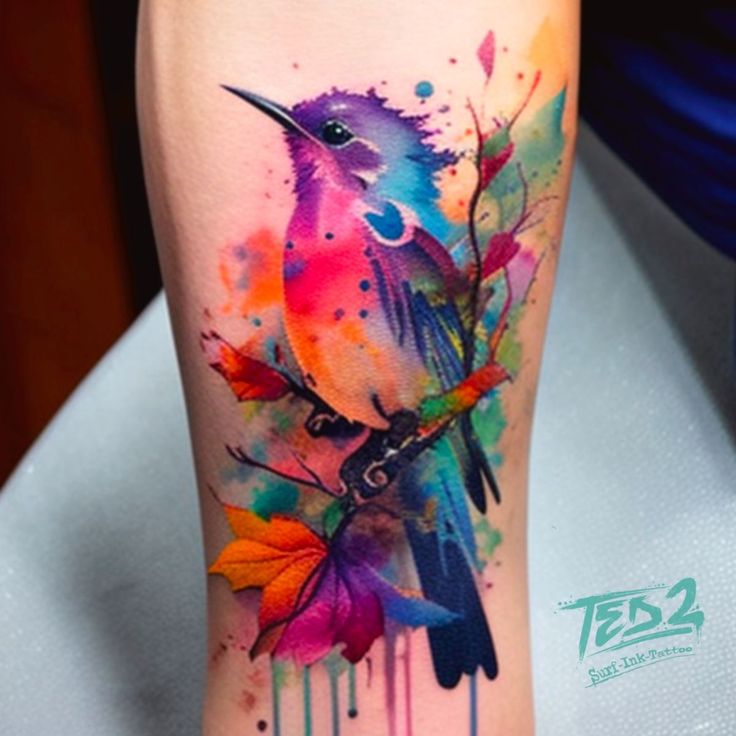 colorful bird tattoo on the leg with watercolor paint drips and leaves around it