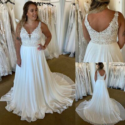 a woman standing in front of a mirror wearing a white dress with lace on it