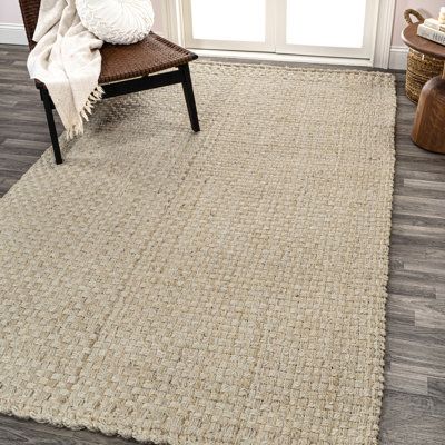 a large rug in the corner of a living room with a chair and window behind it