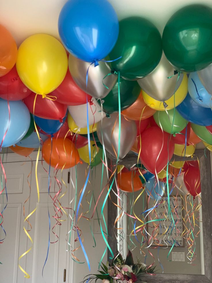 balloons and streamers are hanging from the ceiling in front of a door with a vase full of flowers