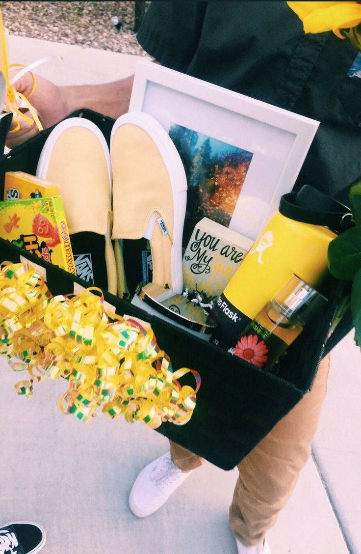 a person holding a basket filled with shoes and other items on the ground in front of them