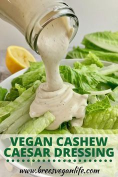 the dressing being poured into a salad with lettuce leaves and lemon wedges