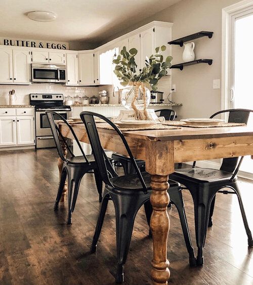 a kitchen with white cabinets and black chairs is pictured in this image, the table has been made out of wood