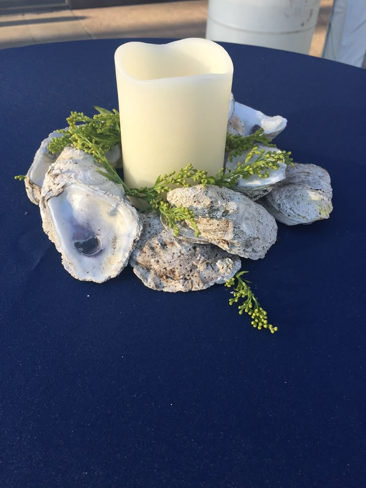 a candle and some rocks are sitting on a table with a blue cloth around it