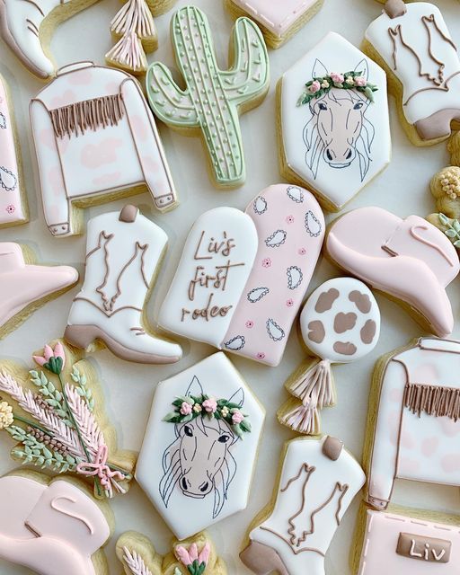 some decorated cookies are laying on a white tablecloth with cactuses and other decorations