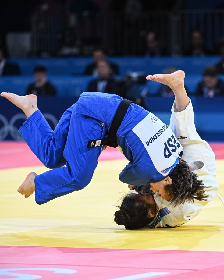 two women in blue and white uniforms are doing a handstand on one another