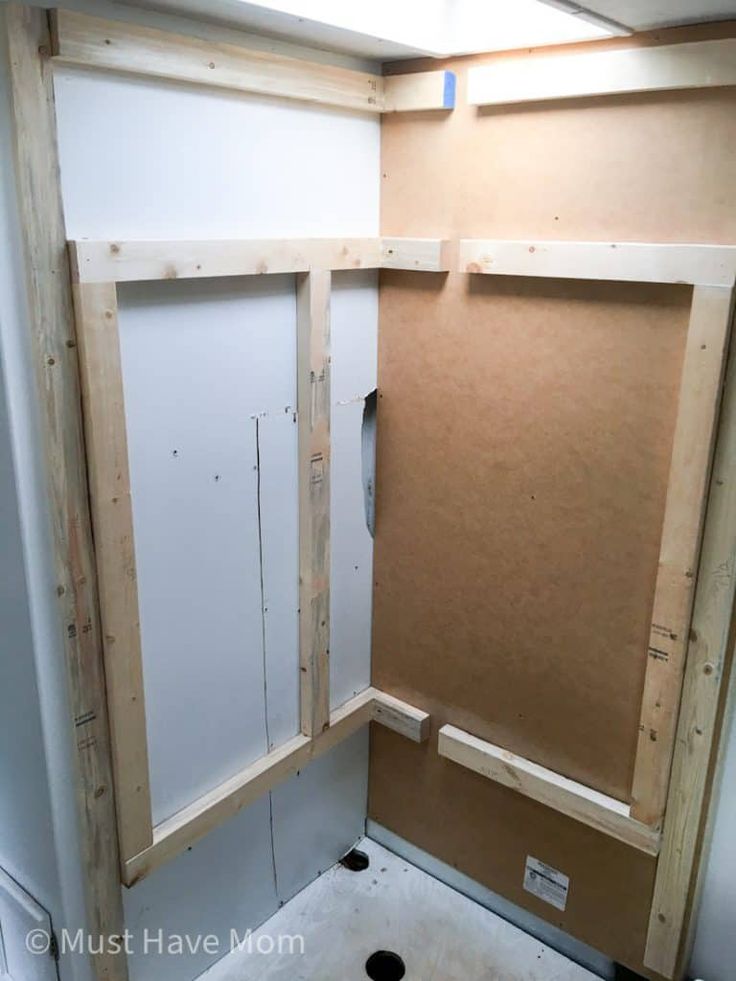 the inside of a bathroom being built with plywood board and studs on the wall