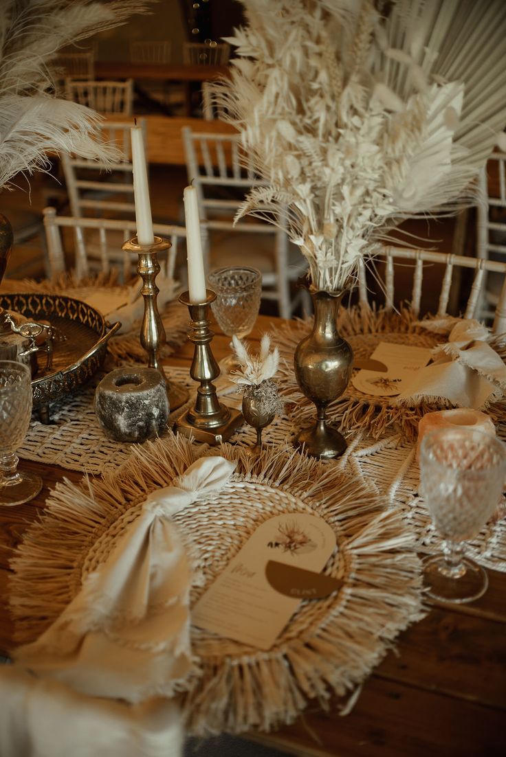 a table topped with lots of white feathers and candlesticks on top of a wooden table