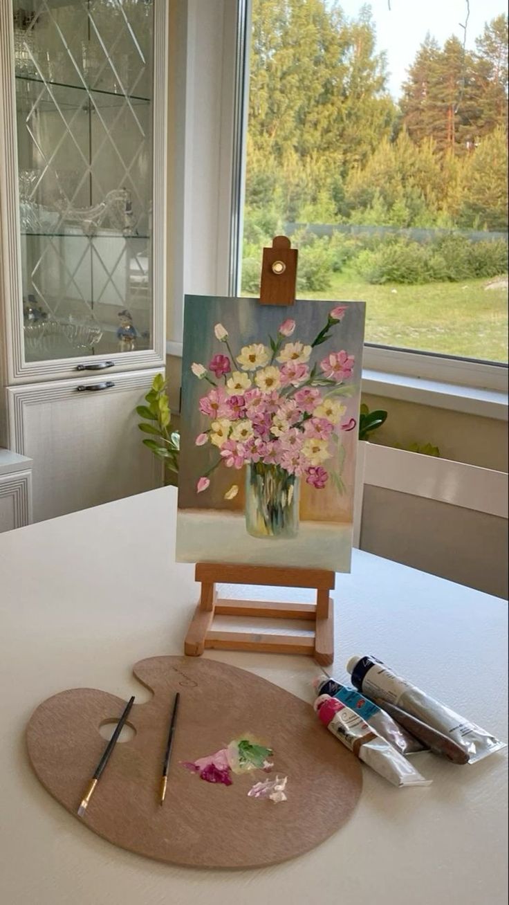 an easel with paint and flowers on it