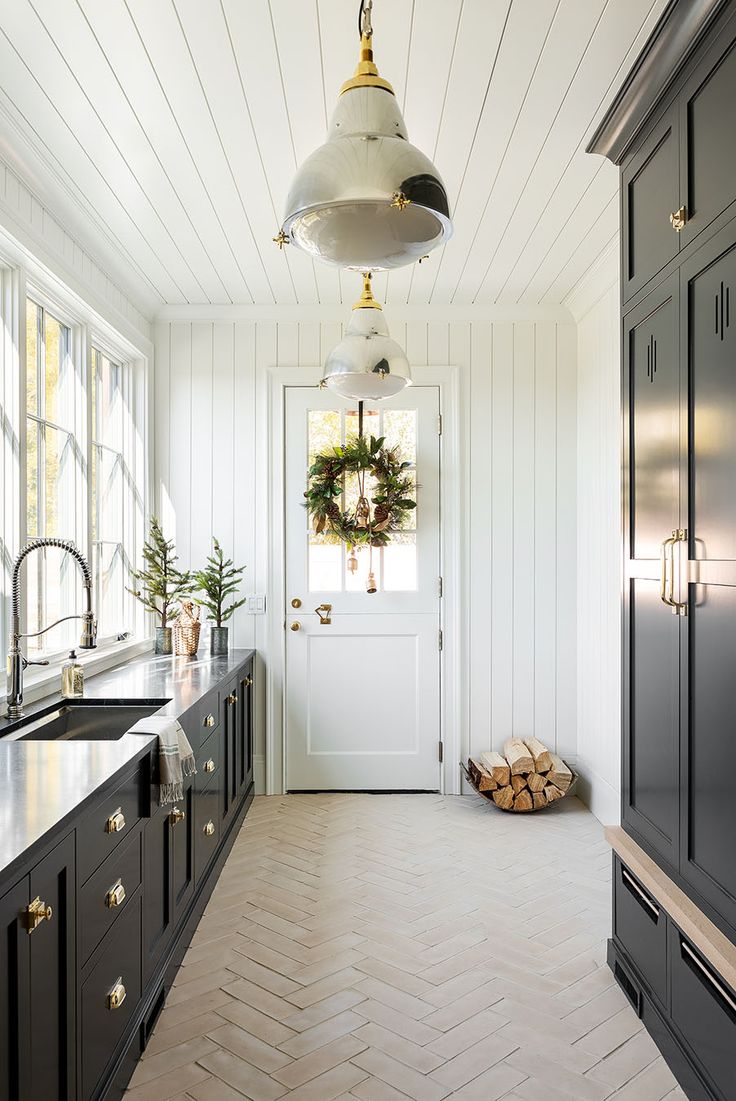 a kitchen with black cabinets and white walls, gold hardware on the door knobs