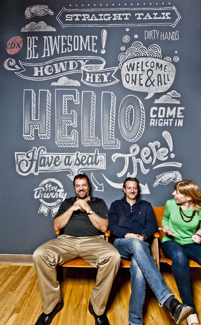 three people sitting in front of a chalk board