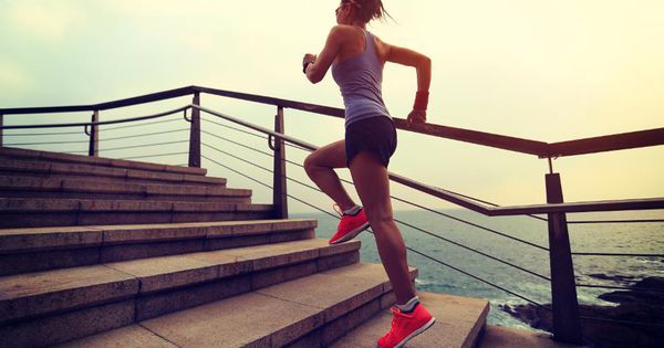 a woman running down some steps by the ocean