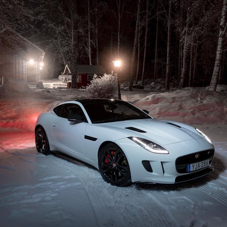 a white sports car parked in the snow at night