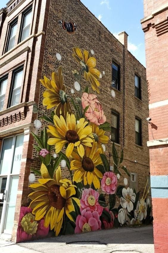 a large mural painted on the side of a brick building with sunflowers and other flowers