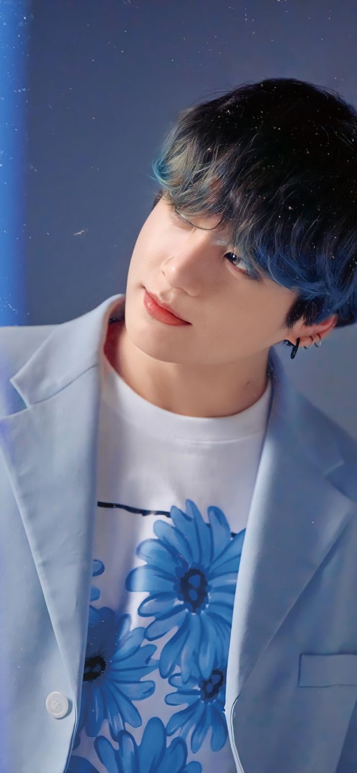 a man with blue hair wearing a white jacket and flower print t - shirt is looking at the camera