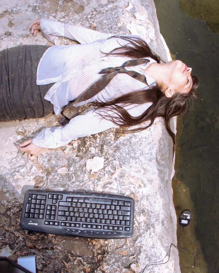 a woman laying on top of a rock next to a keyboard