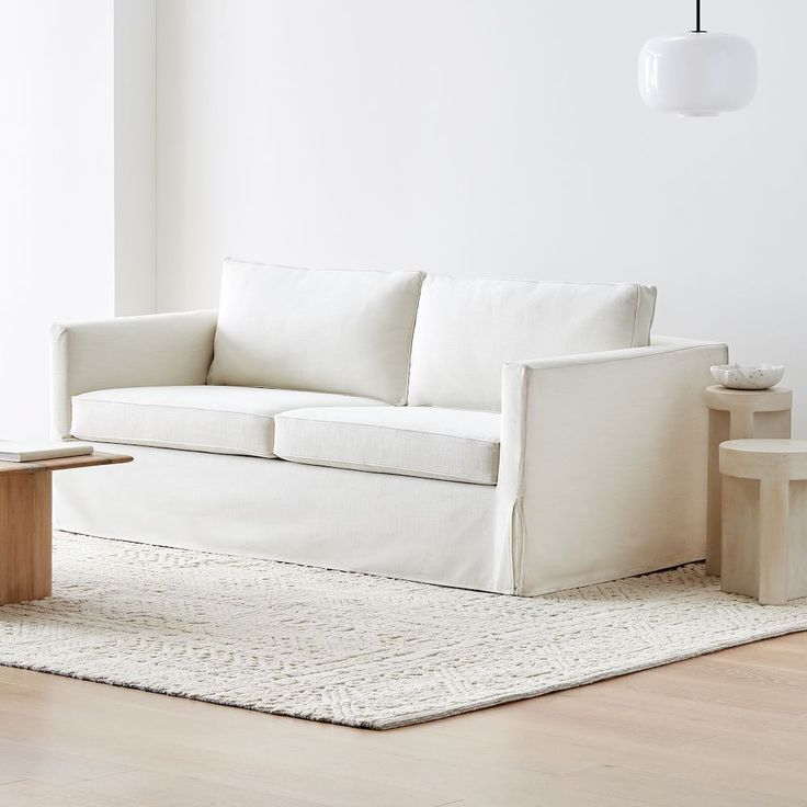 a white couch sitting on top of a hard wood floor next to a coffee table