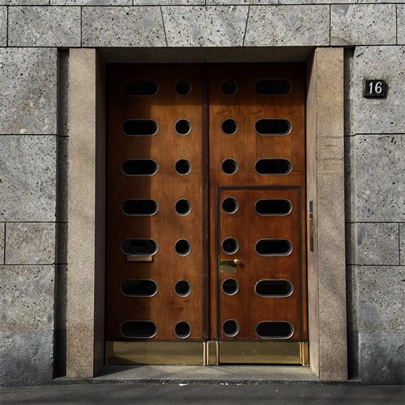 an open door on the side of a building with metal bars and holes in it