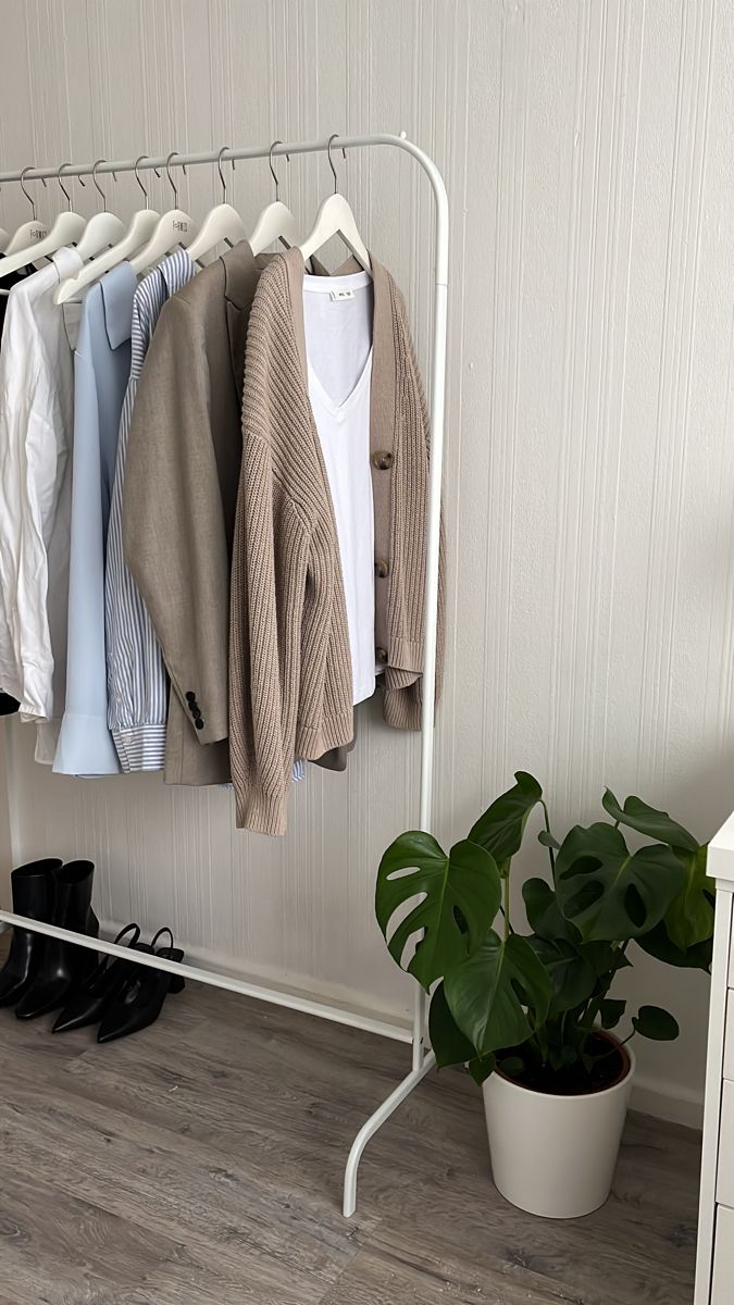 an ironing board with clothes hanging on it and a potted plant next to it