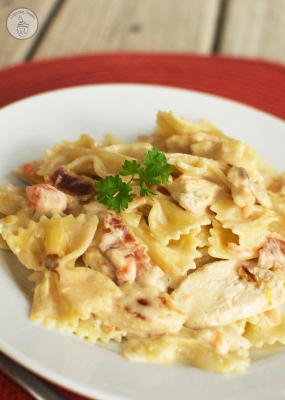 a white plate topped with pasta covered in chicken and sauce on top of a red place mat