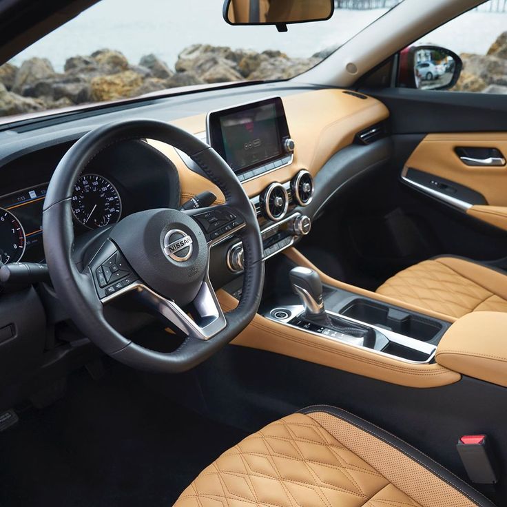 the interior of a car with tan leather and black trims, including steering wheel