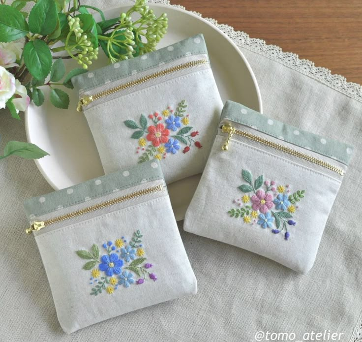 three embroidered purses on a table with flowers