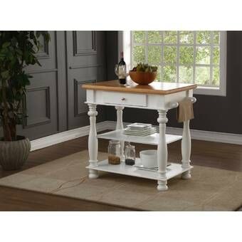 a white kitchen island with wooden top and shelves on the bottom, next to a potted plant