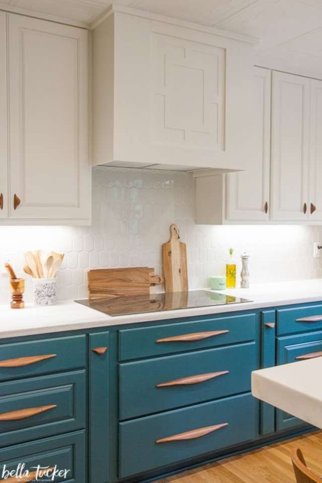 a kitchen with blue cabinets and white counter tops is pictured in this image, there are wooden utensils on the counters