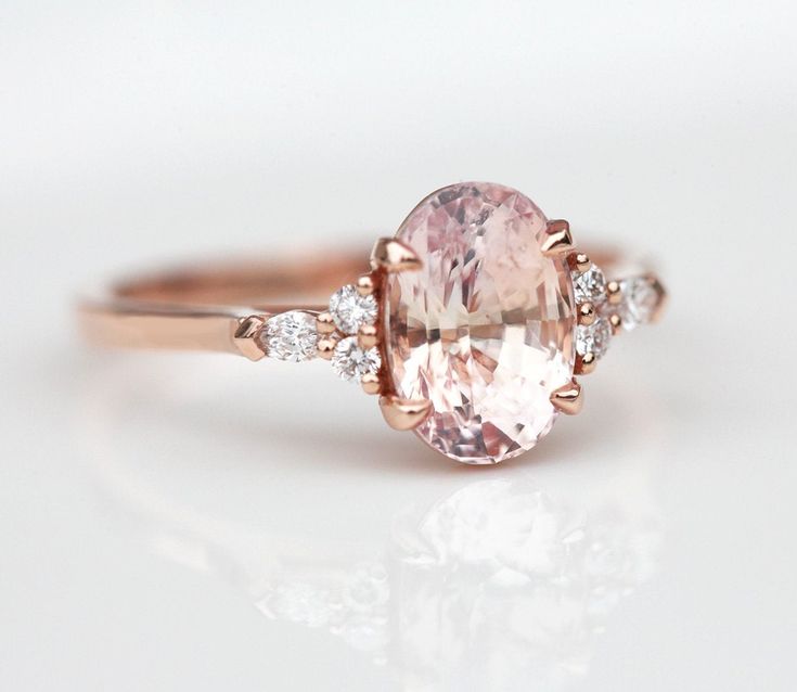 an oval shaped pink diamond ring with three diamonds around it