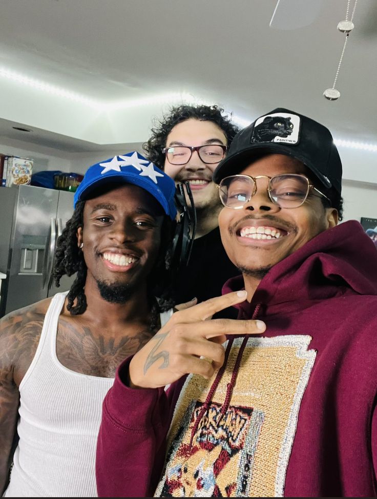 three men are posing for the camera with one man pointing at his ear and smiling