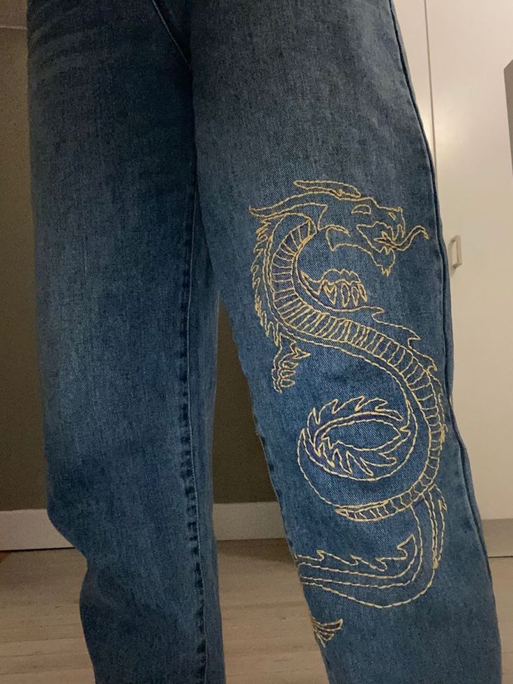 a person wearing blue jeans with a dragon drawn on the side of their pants and shoes